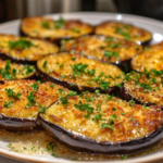 Crispy golden-brown eggplant slices topped with fresh herbs on a white plate