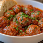 A bowl of meatballs in rich tomato sauce, garnished with fresh herbs and served with crusty bread. (Easy recipes with frozen meatballs)