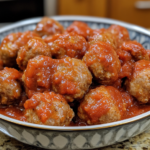 A bowl filled with crockpot-cooked meatballs coated in a rich tomato sauce. (Crockpot Frozen Meatballs Recipe)